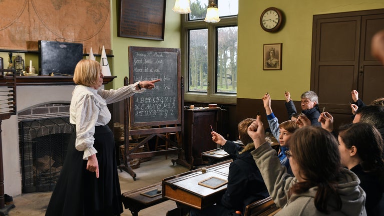 Costumed interpreter as the school mistress and visitors in the recreated Victorian classroom at Sudbury Hall and the National Trust Museum of Childhood, Derbyshire
